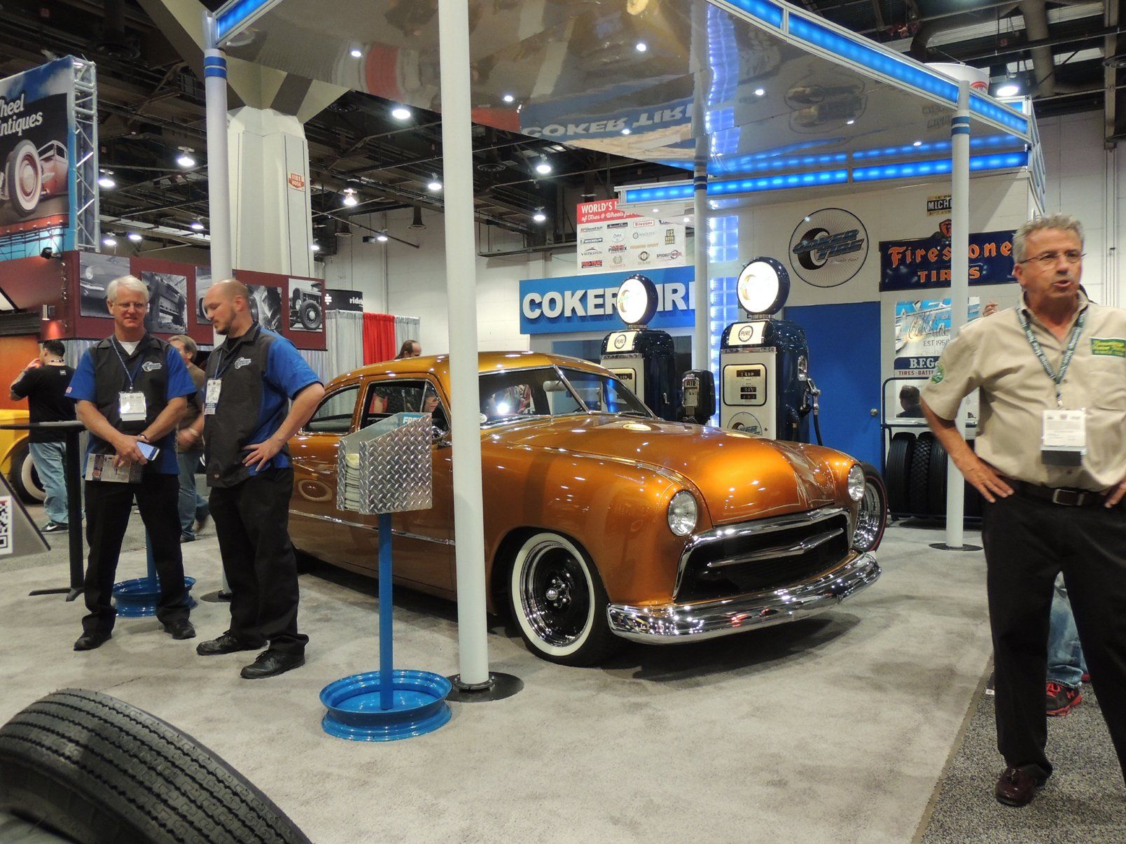 A group of men are standing around a car at a car show