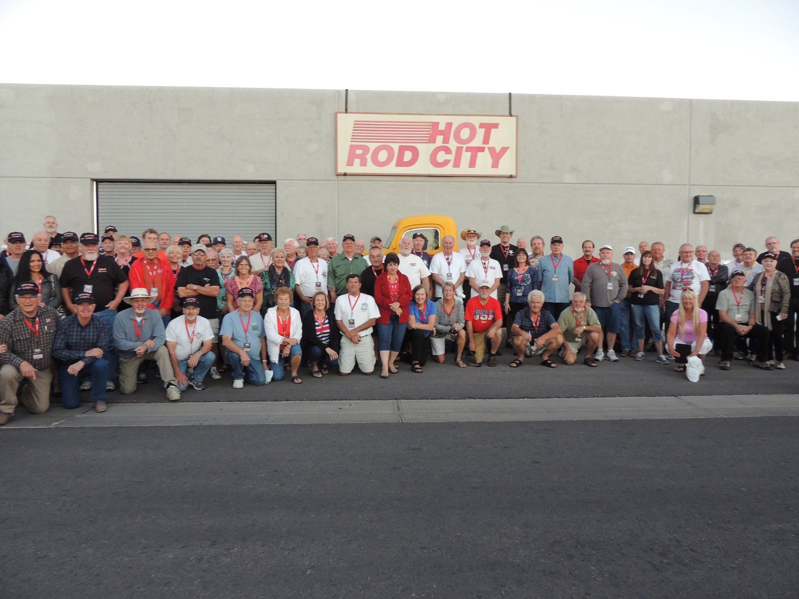 A group of people posing in front of a building that says hot rod city