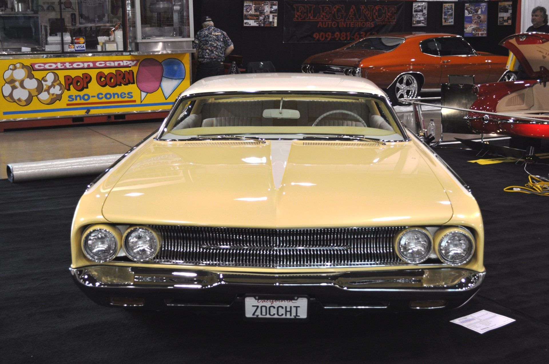 A yellow car is parked in front of a cotton candy stand