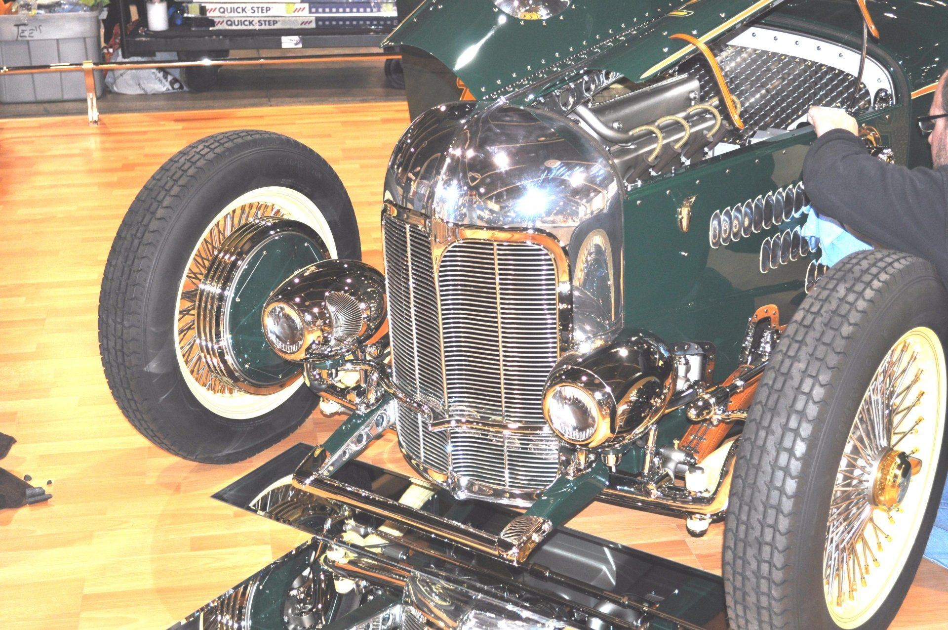 A man is working on the front of a green car