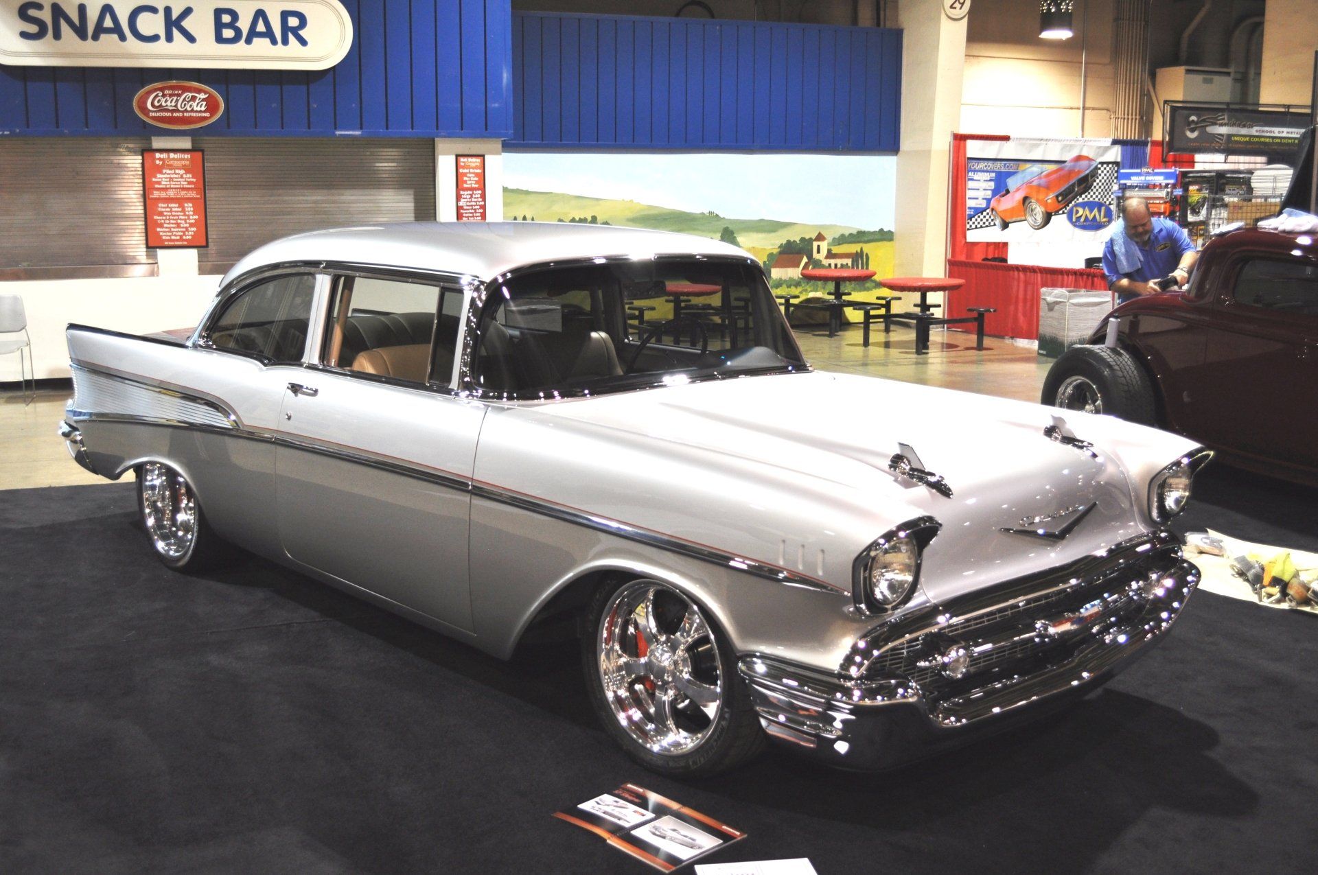 A silver car is parked in front of a snack bar
