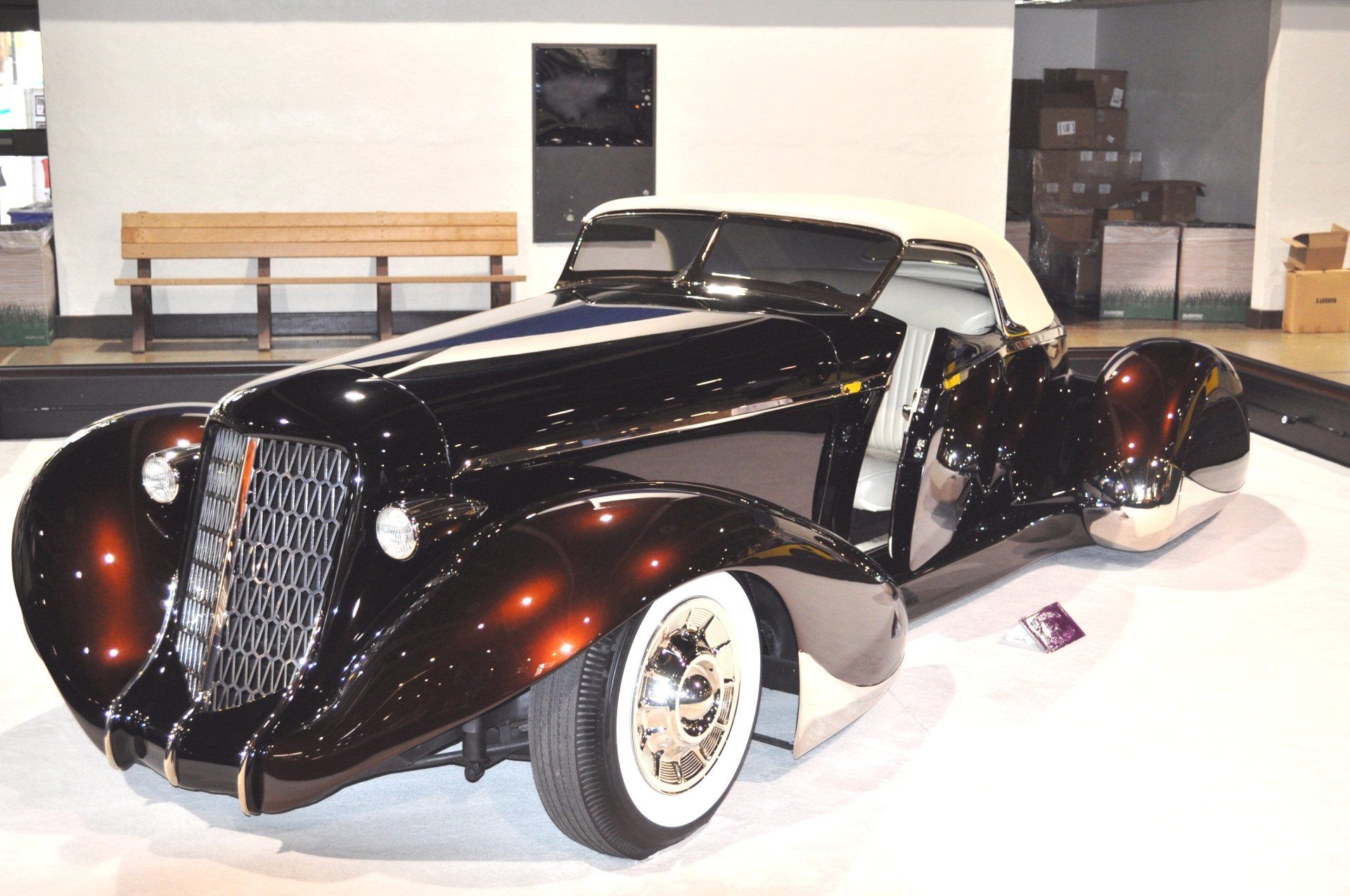 A black car with white tires is parked in a room