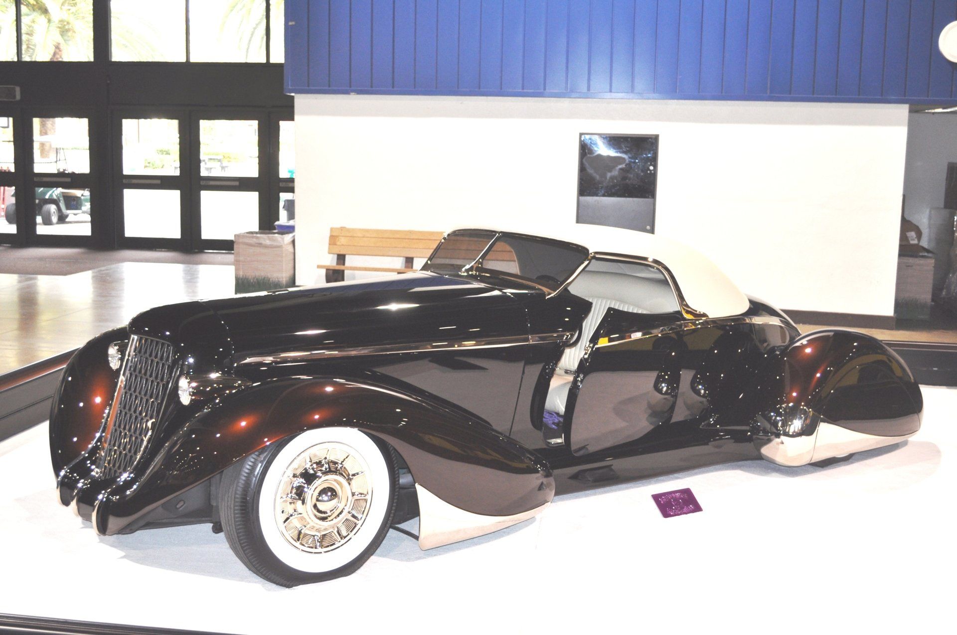 A black car with white tires is parked in a room