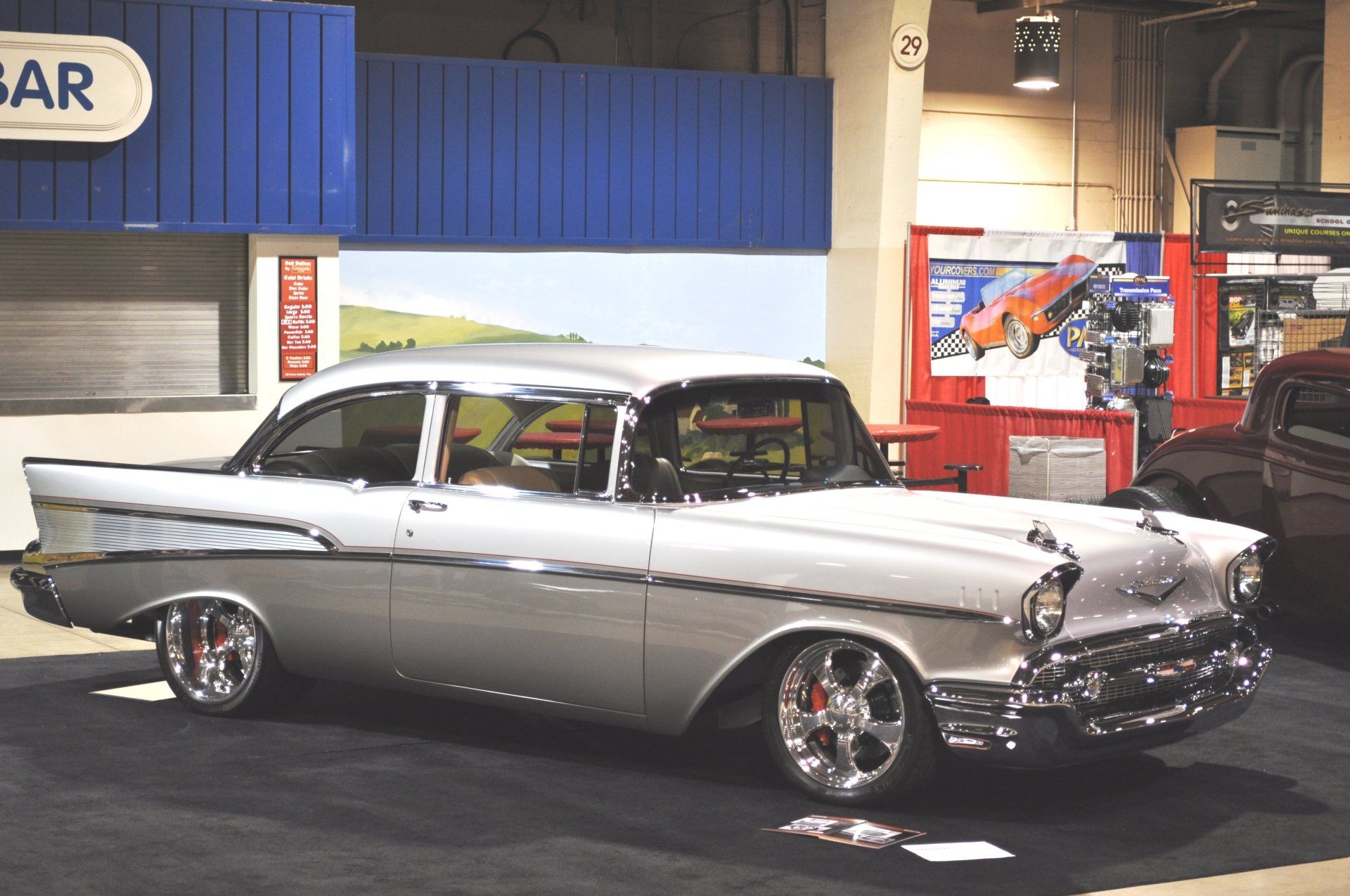 A silver car is parked in front of a sign that says car