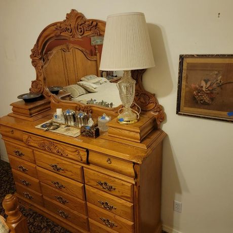 Wooden dresser with mirror, lamp, and artwork in a room.