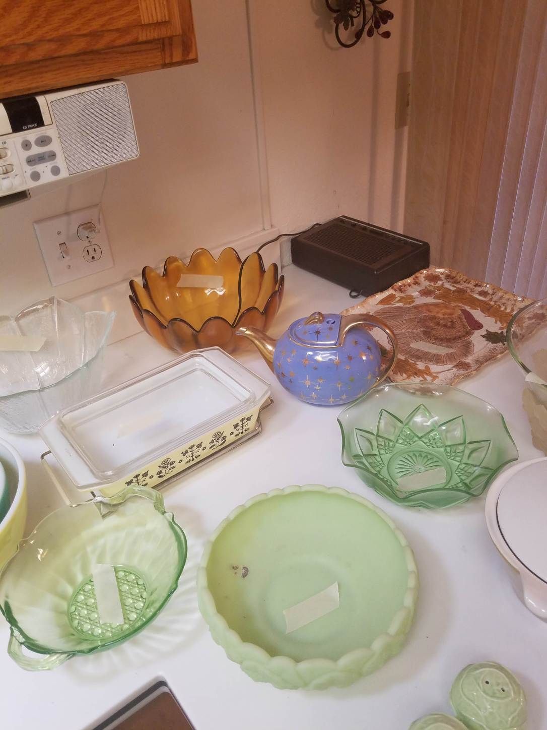 Various colored glass bowls, platters, and serving dishes on a white countertop in a kitchen setting.