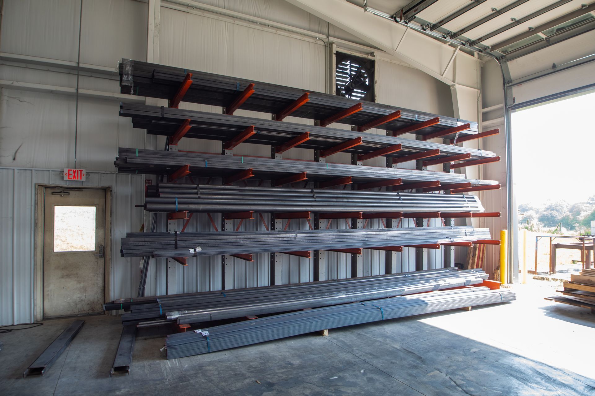 Metal bars stored on cantilever racking in a warehouse; gray and red colors.