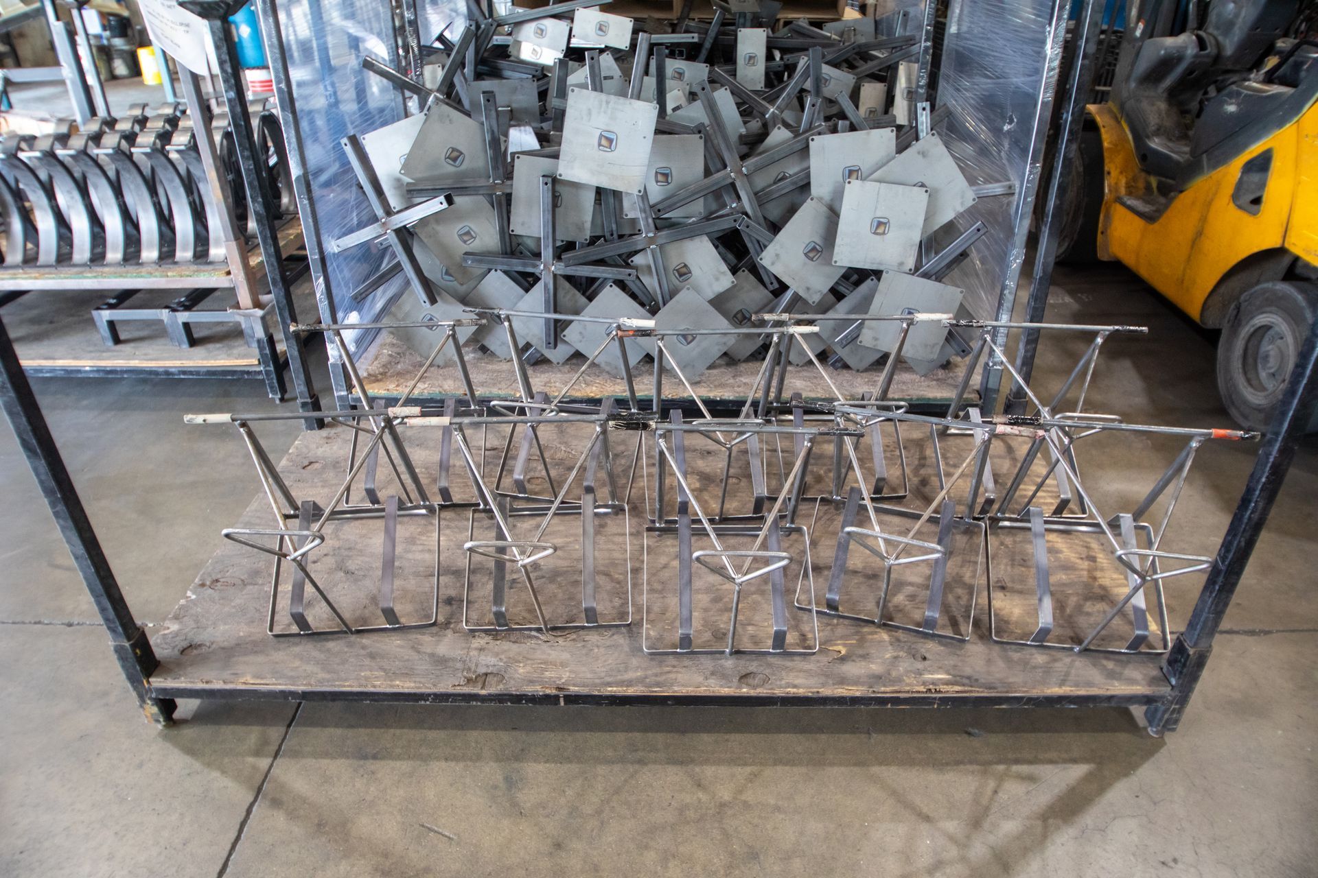 Metal parts stacked on a wooden pallet; a forklift is visible nearby.