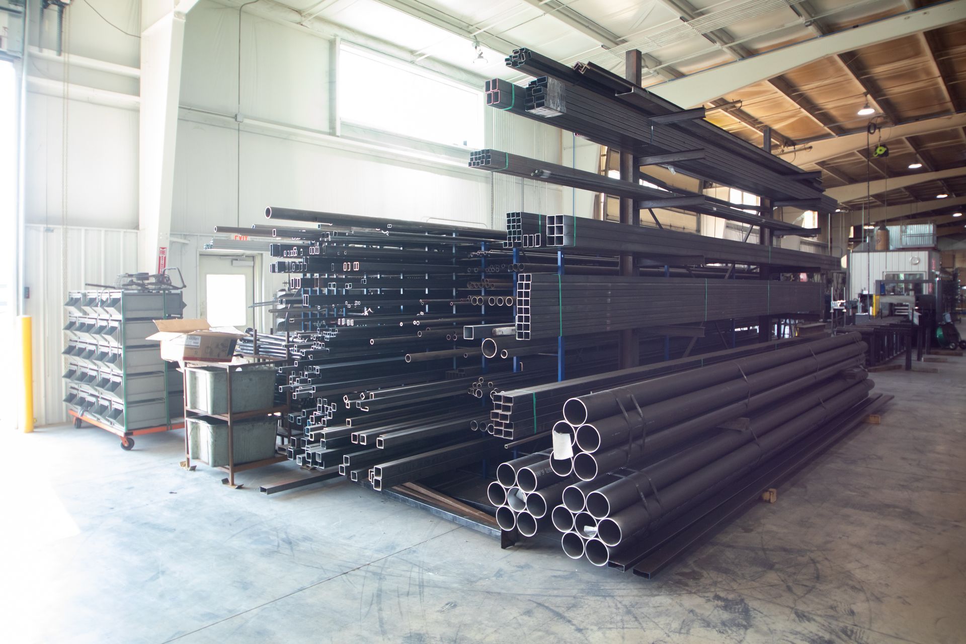 Steel beams and pipes stored on racks in a warehouse.