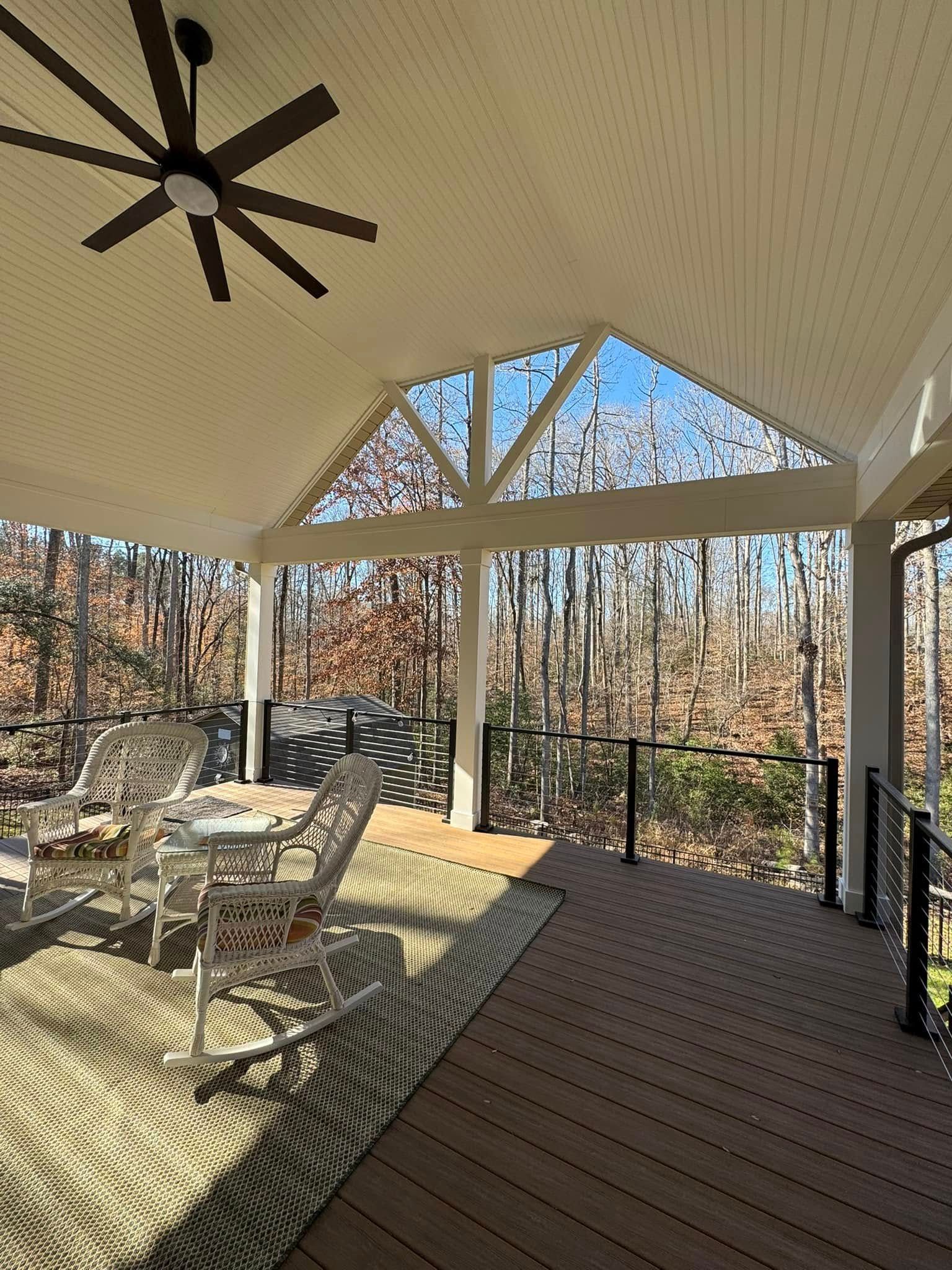 A porch with a ceiling fan and a table and chairs on it.