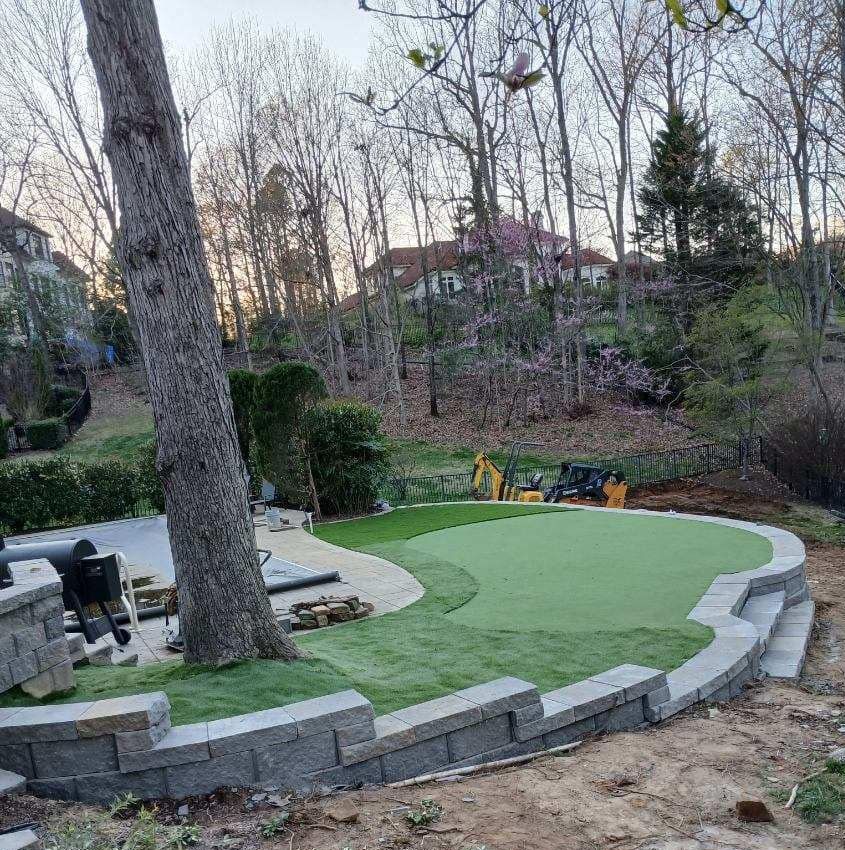 A green putting green is being built in a backyard.