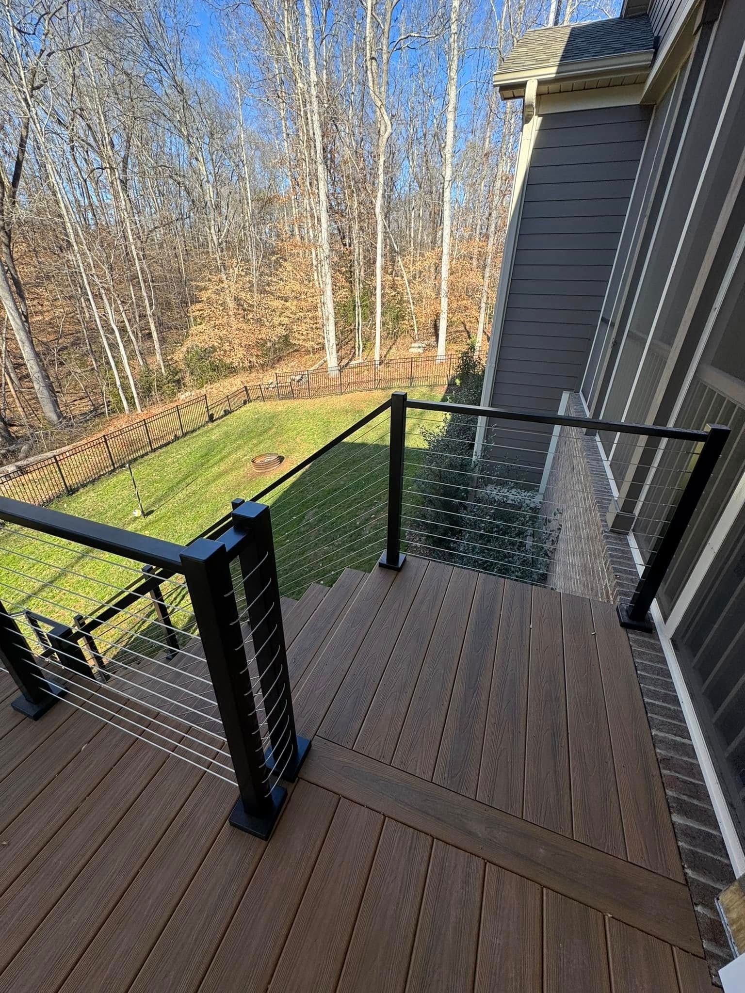 A wooden deck with stairs leading up to it and a glass railing.