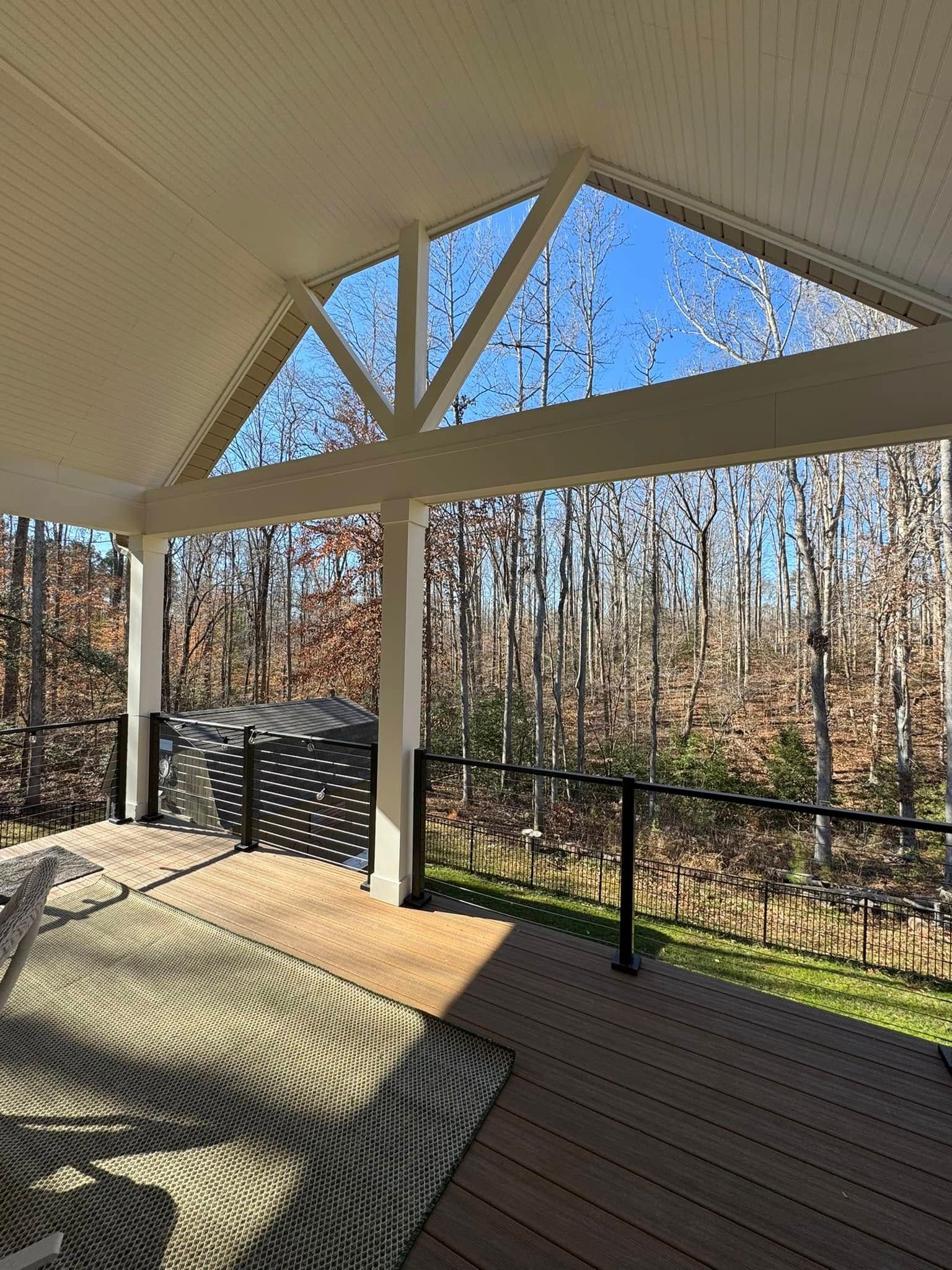 A covered deck with a view of a forest and trees.