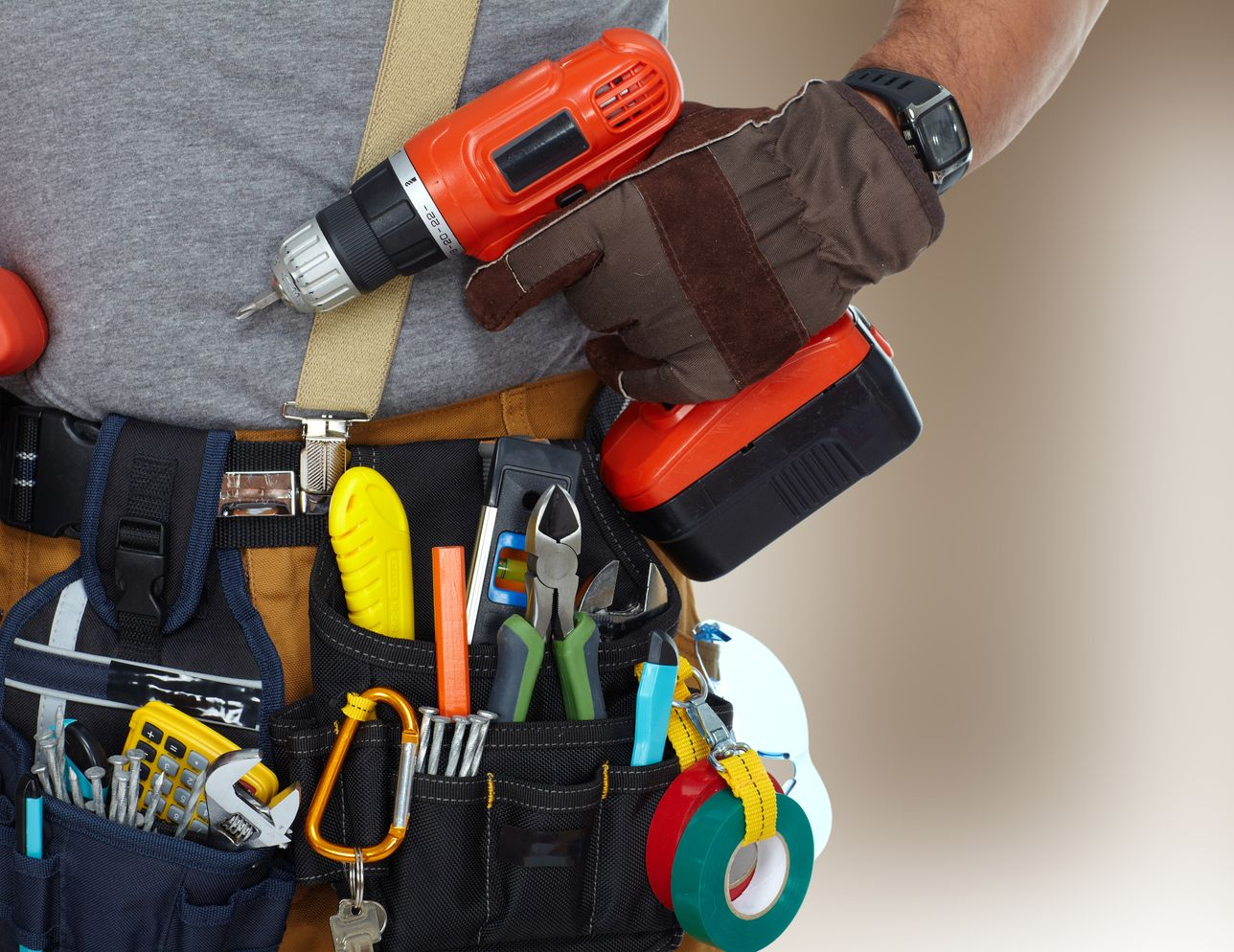 Person wearing a tool belt, holding a red drill, with a light background.