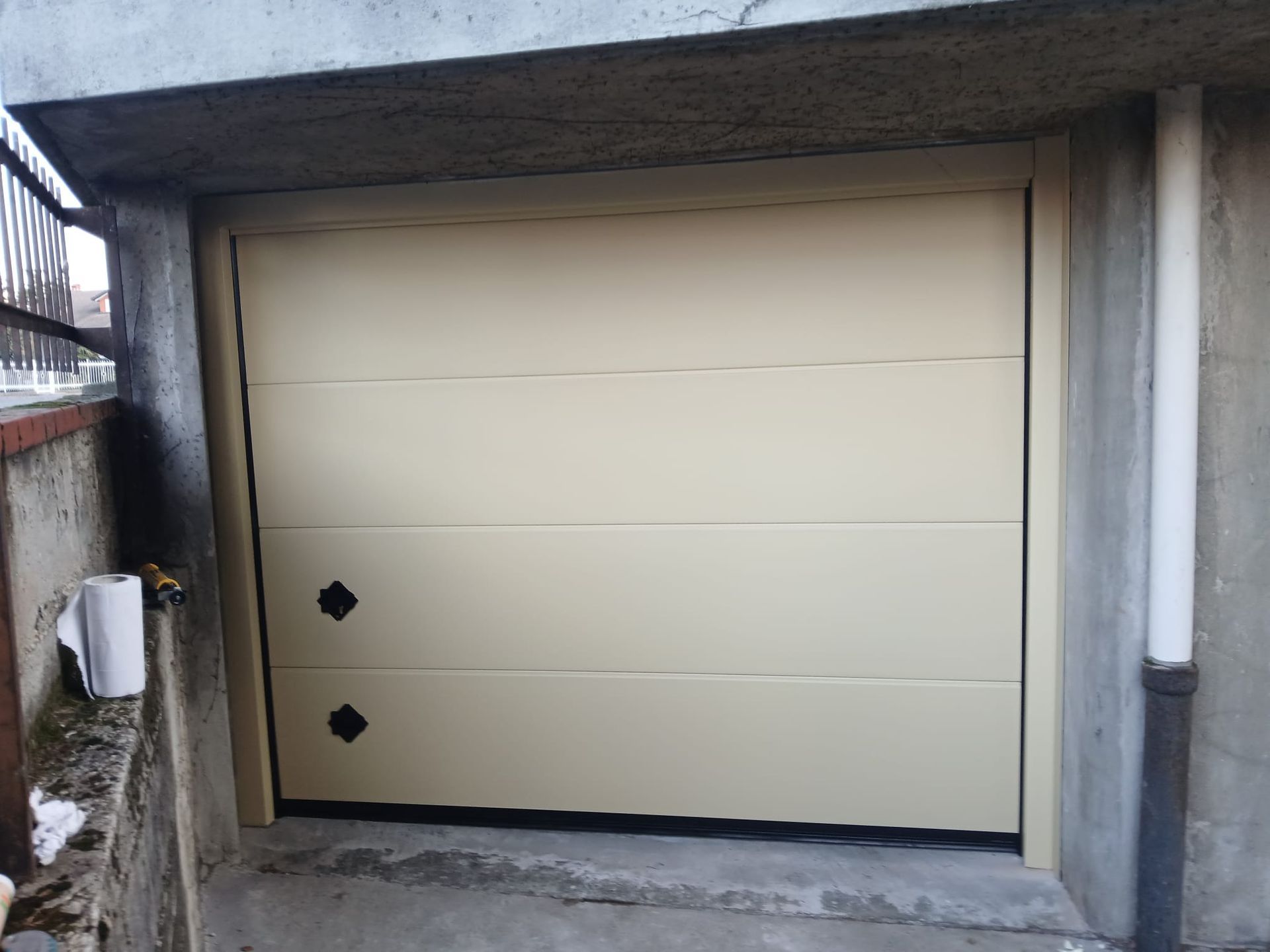 Uno showroom con pavimento effetto legno, pareti dipinte a strisce turchesi e bianche, una porta da garage marrone e porte in legno in esposizione.