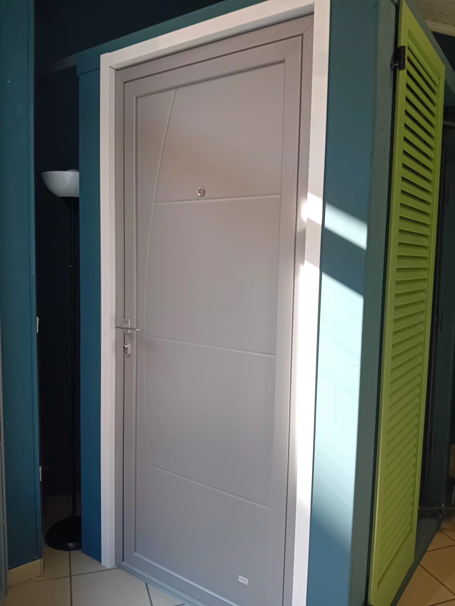 Due porte interne chiuse una accanto all'altra: una grigio opaco con linee geometriche, l'altra con venature di legno scuro su una parete verde.