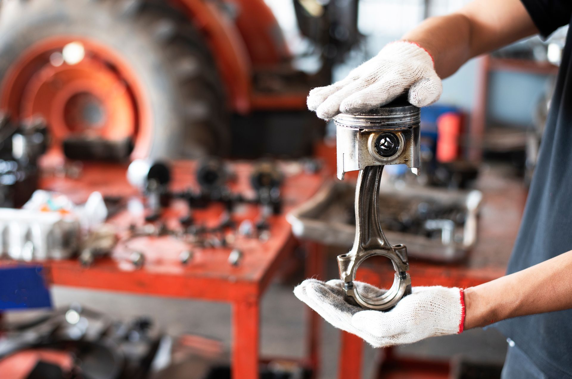 A man is holding a piston in his hand in a garage.