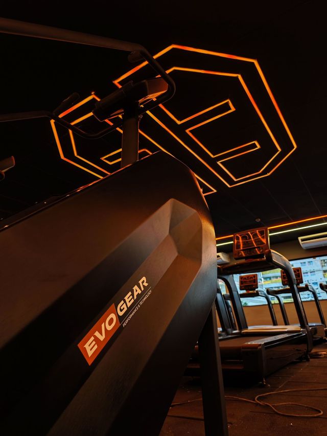 A treadmill in a gym evogear with an evo gear logo on the roof.