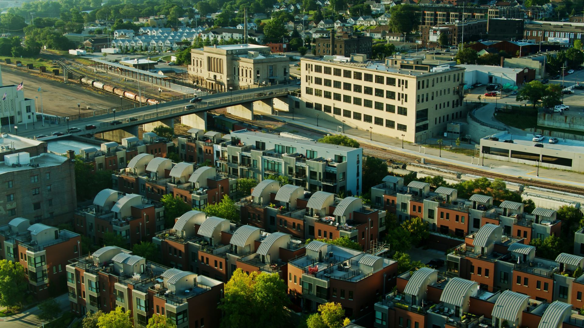 Aerial view of a city with residential buildings, industrial structures, and a railway line.