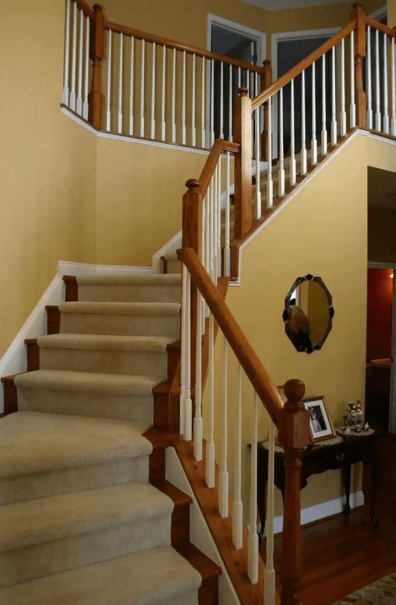 A staircase with a wooden railing and a mirror on the wall