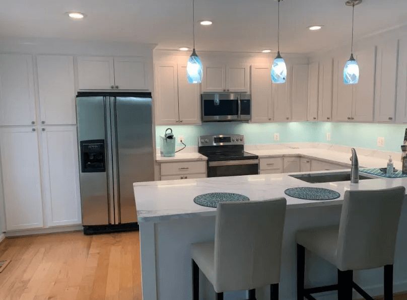 A kitchen with white cabinets , stainless steel appliances , a refrigerator and a sink.
