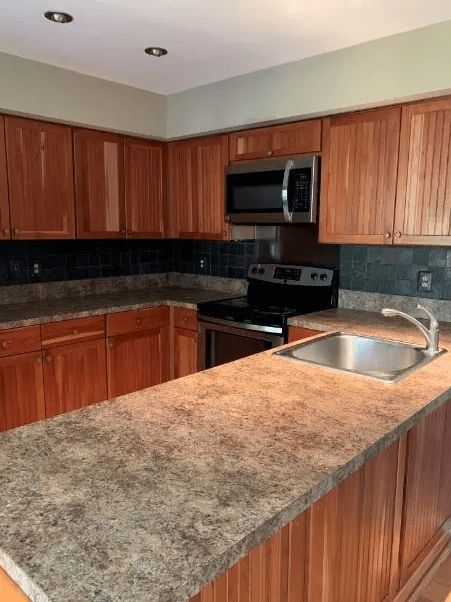 An empty kitchen with wooden cabinets and granite counter tops