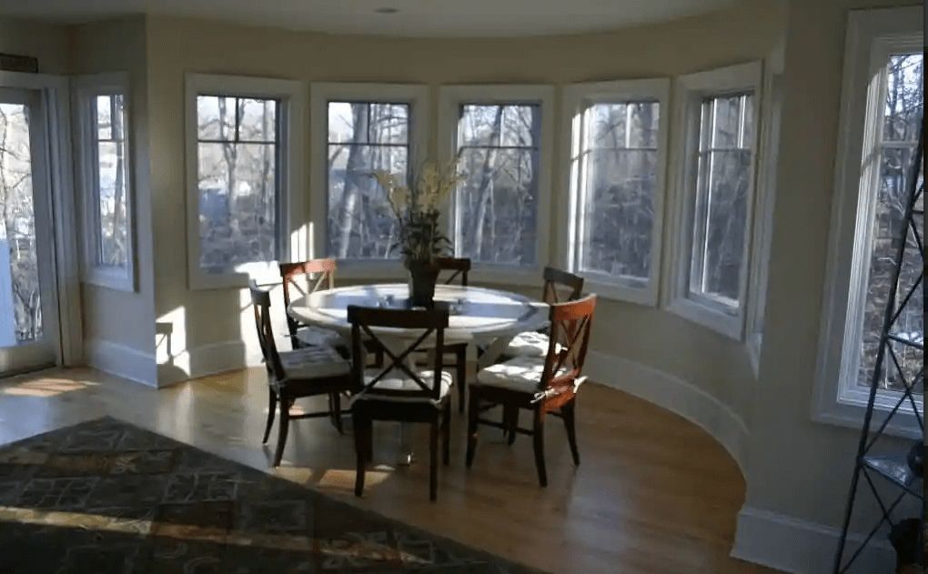 A dining room with a table and chairs and lots of windows