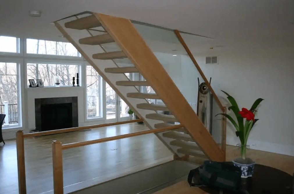 A wooden staircase with a glass railing in a living room