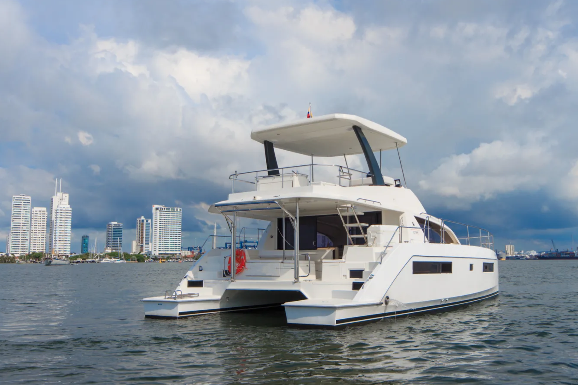 A white yacht is floating on top of a body of water with a city in the background.