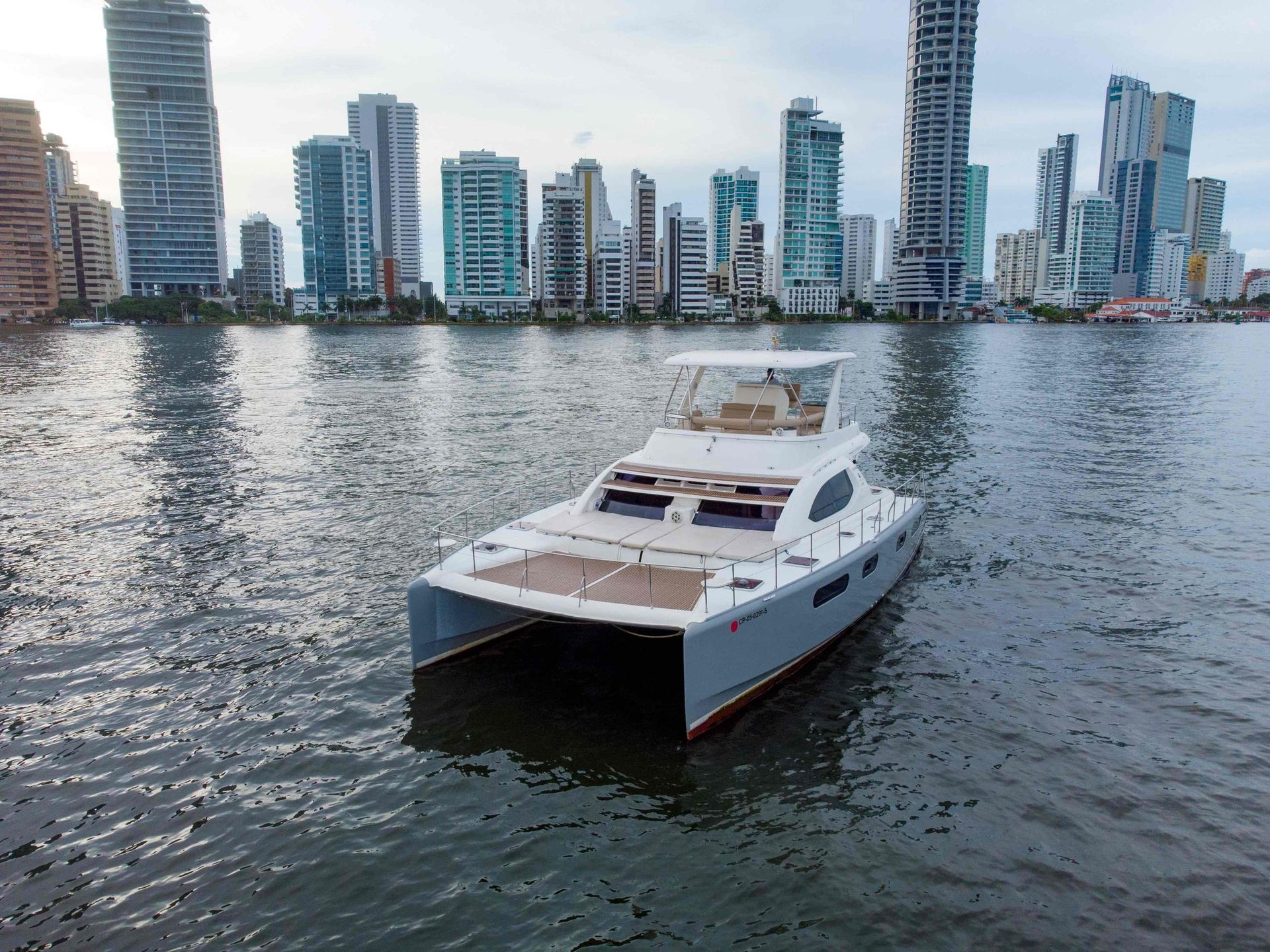 A boat is floating on a body of water in front of a city skyline.