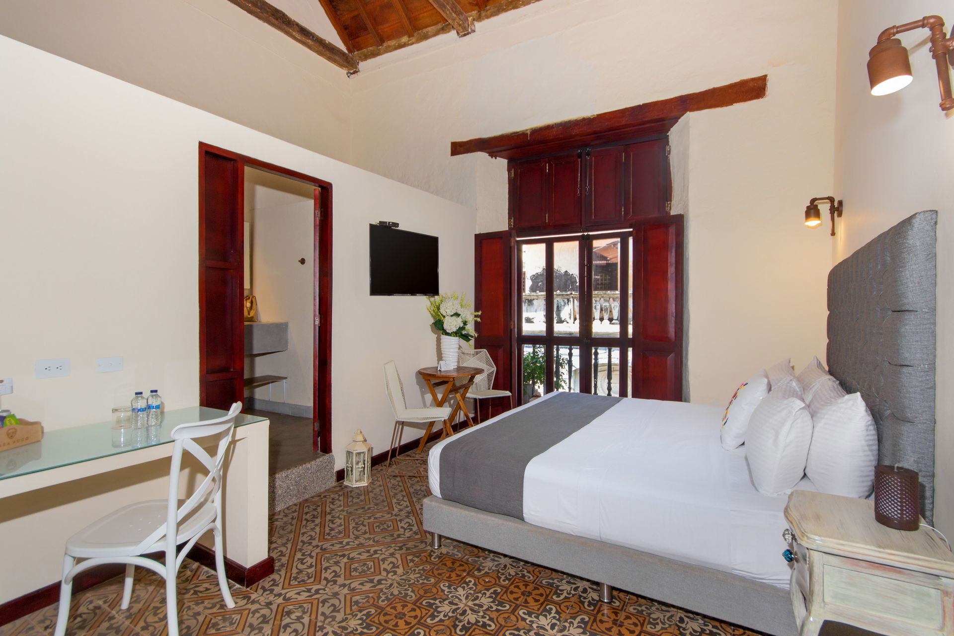 A hotel room with a bed , desk , chair and television.