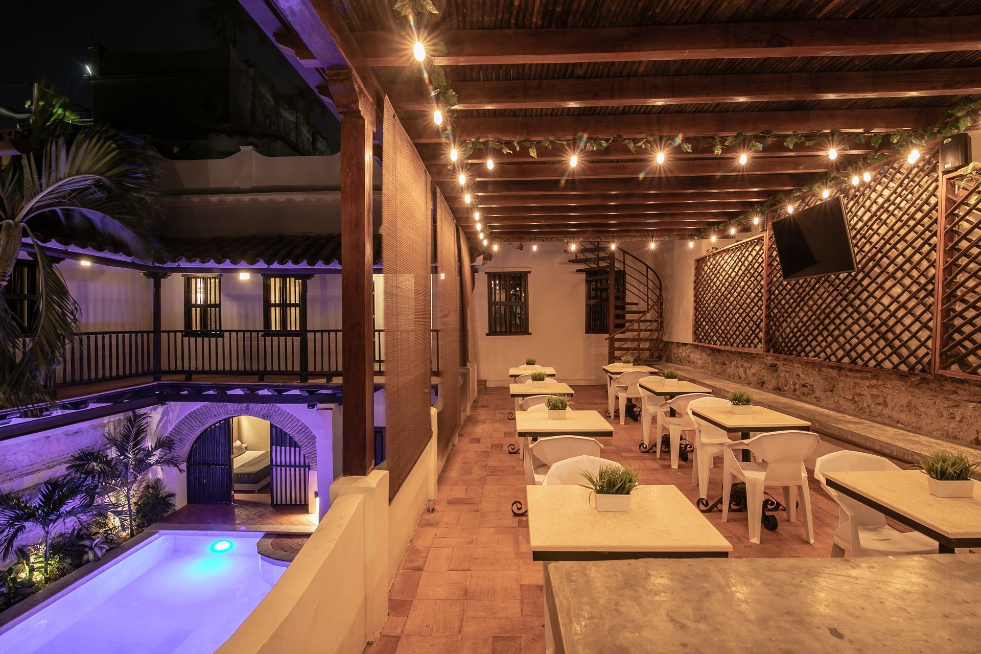 A restaurant with tables and chairs and a swimming pool at night.