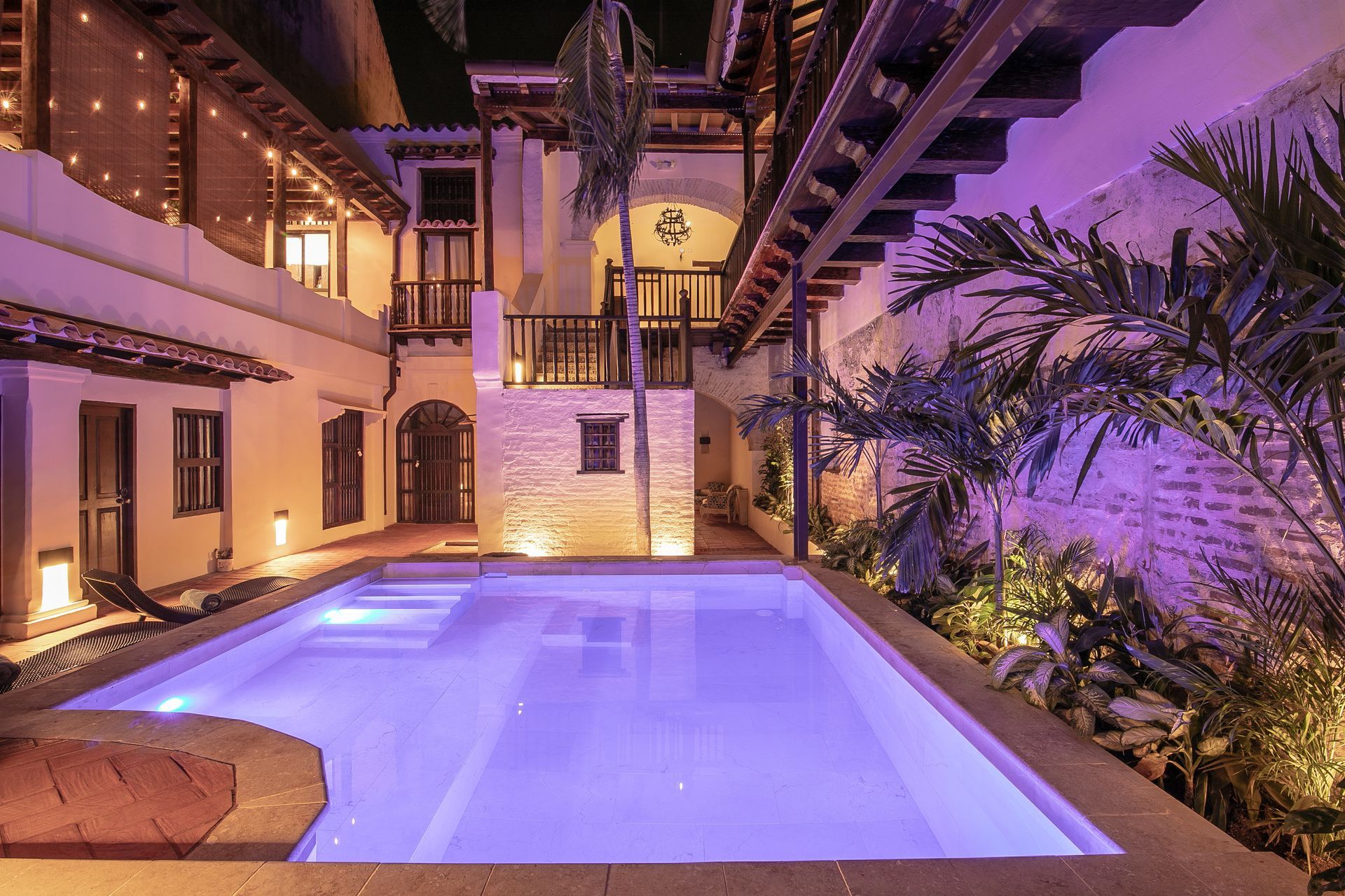 A large swimming pool is lit up at night in front of a building.