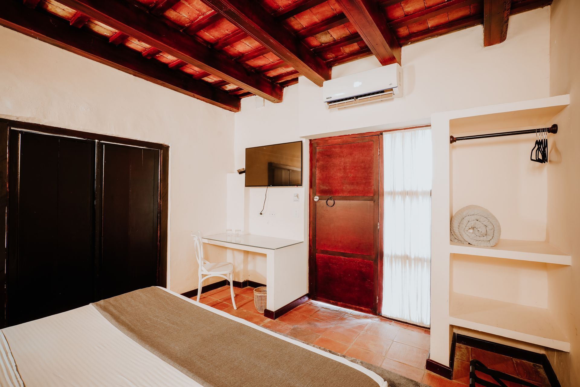 A bedroom with a king size bed , a desk , and a window.