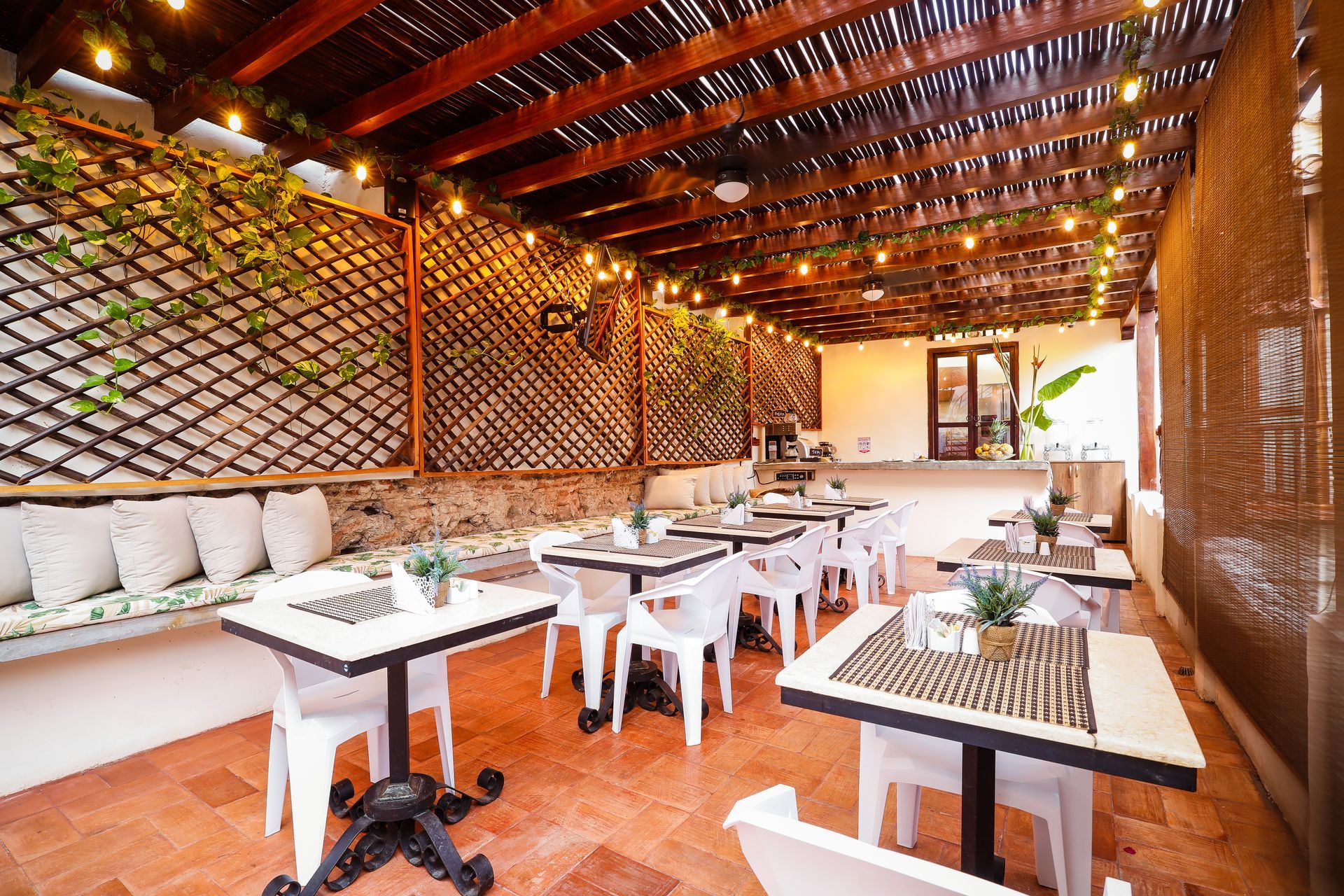 A restaurant with tables and chairs under a wooden roof.