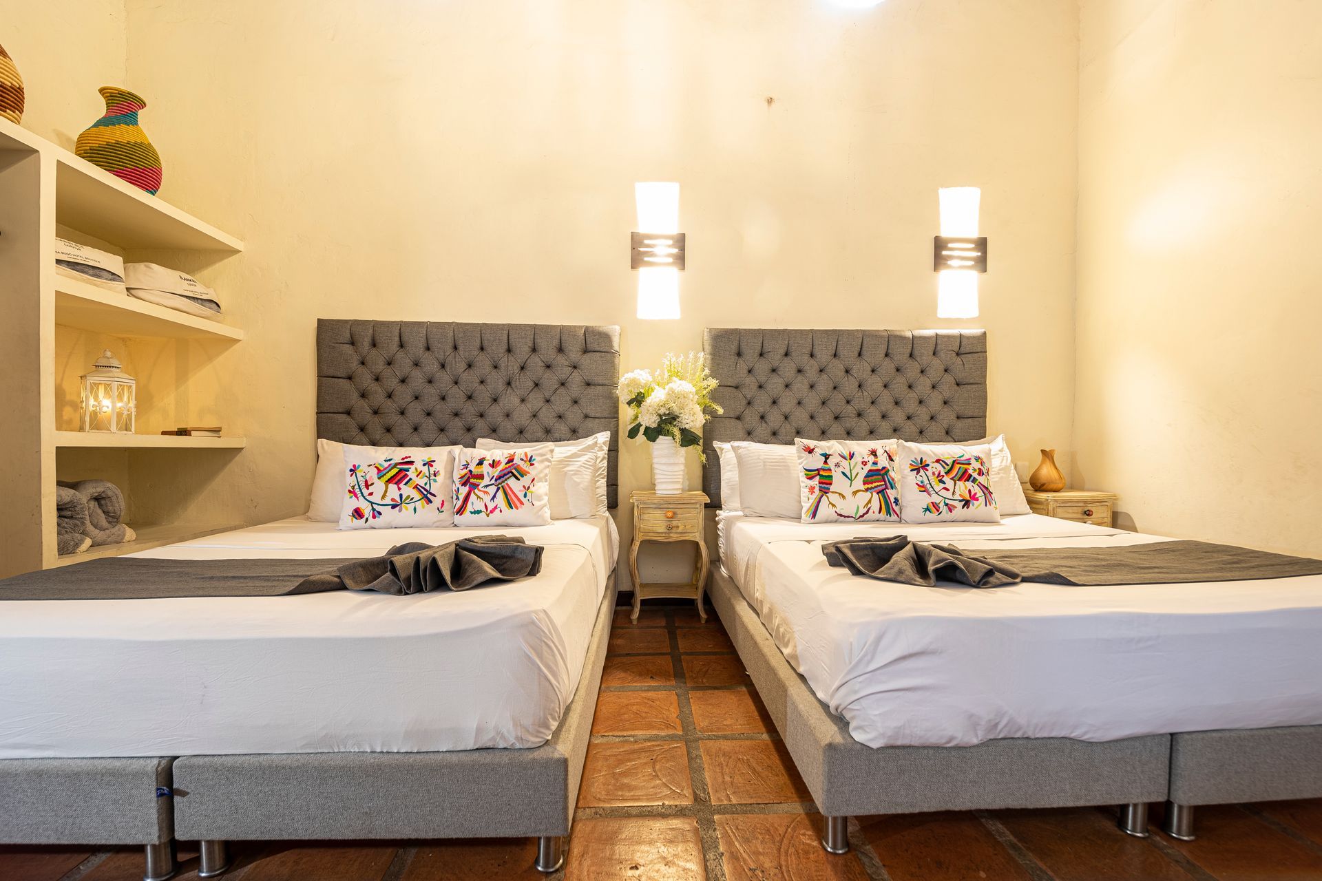 A hotel room with two beds and a tiled floor.