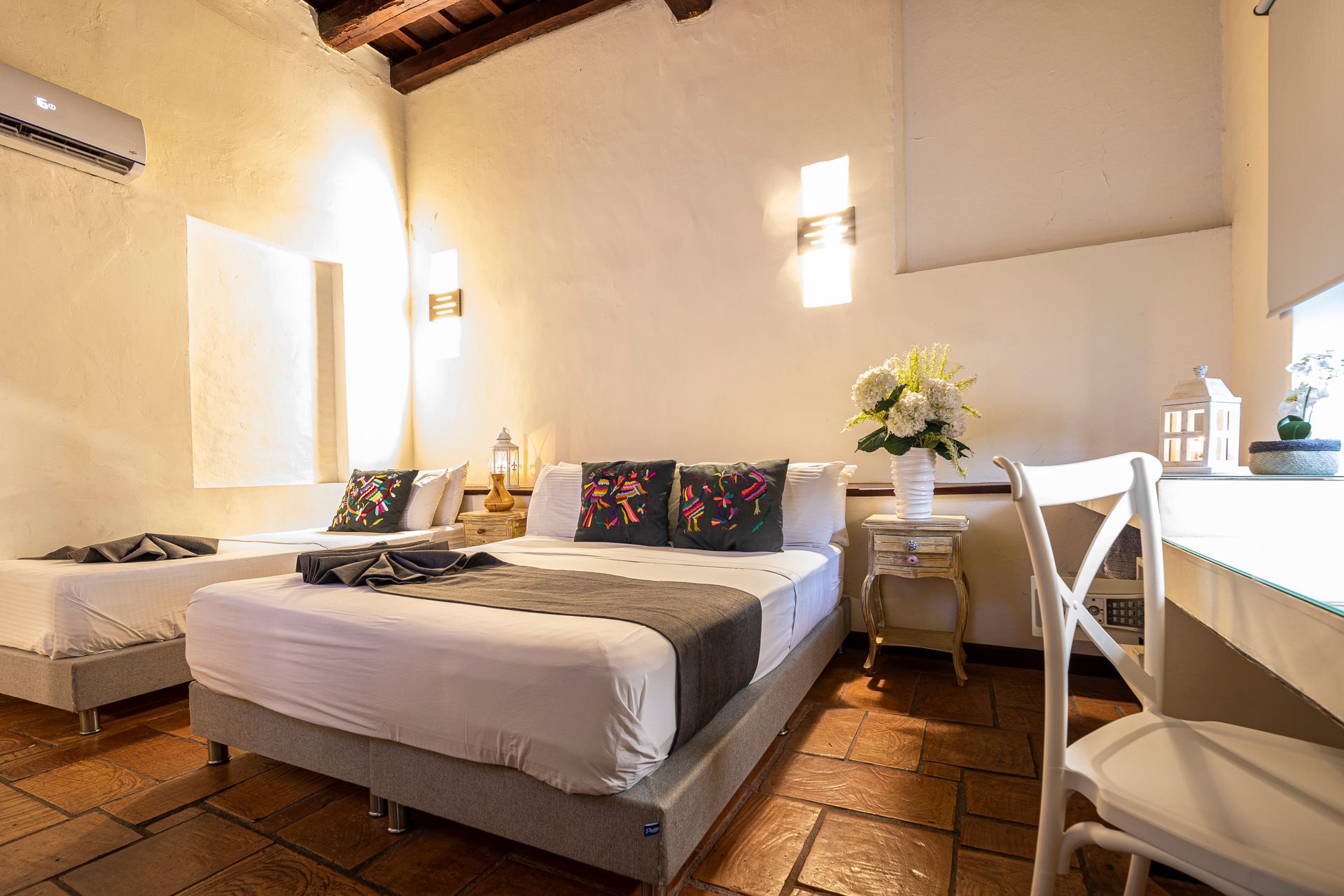 A hotel room with three beds and a desk.