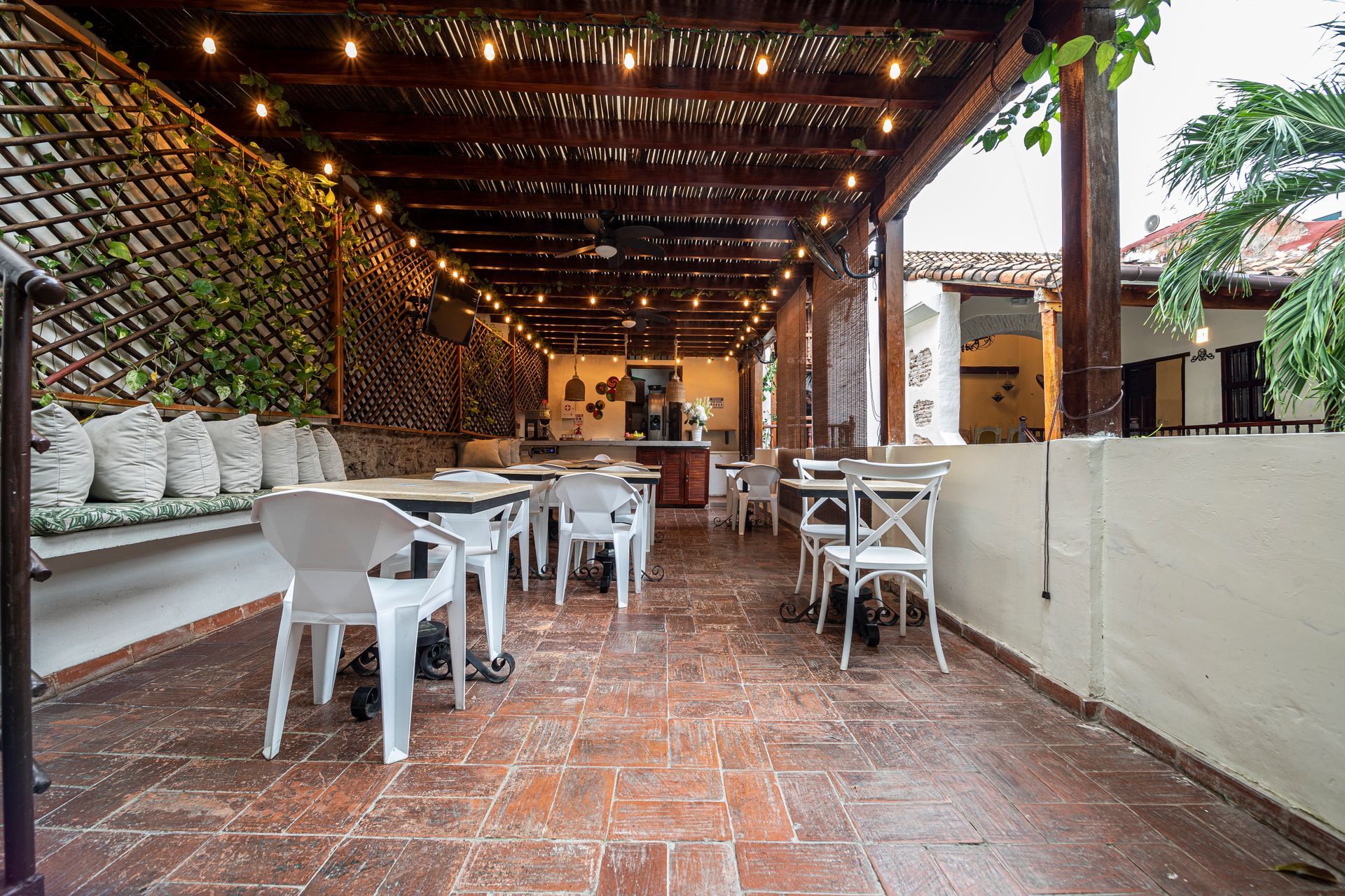 A restaurant with tables and chairs under a wooden roof.