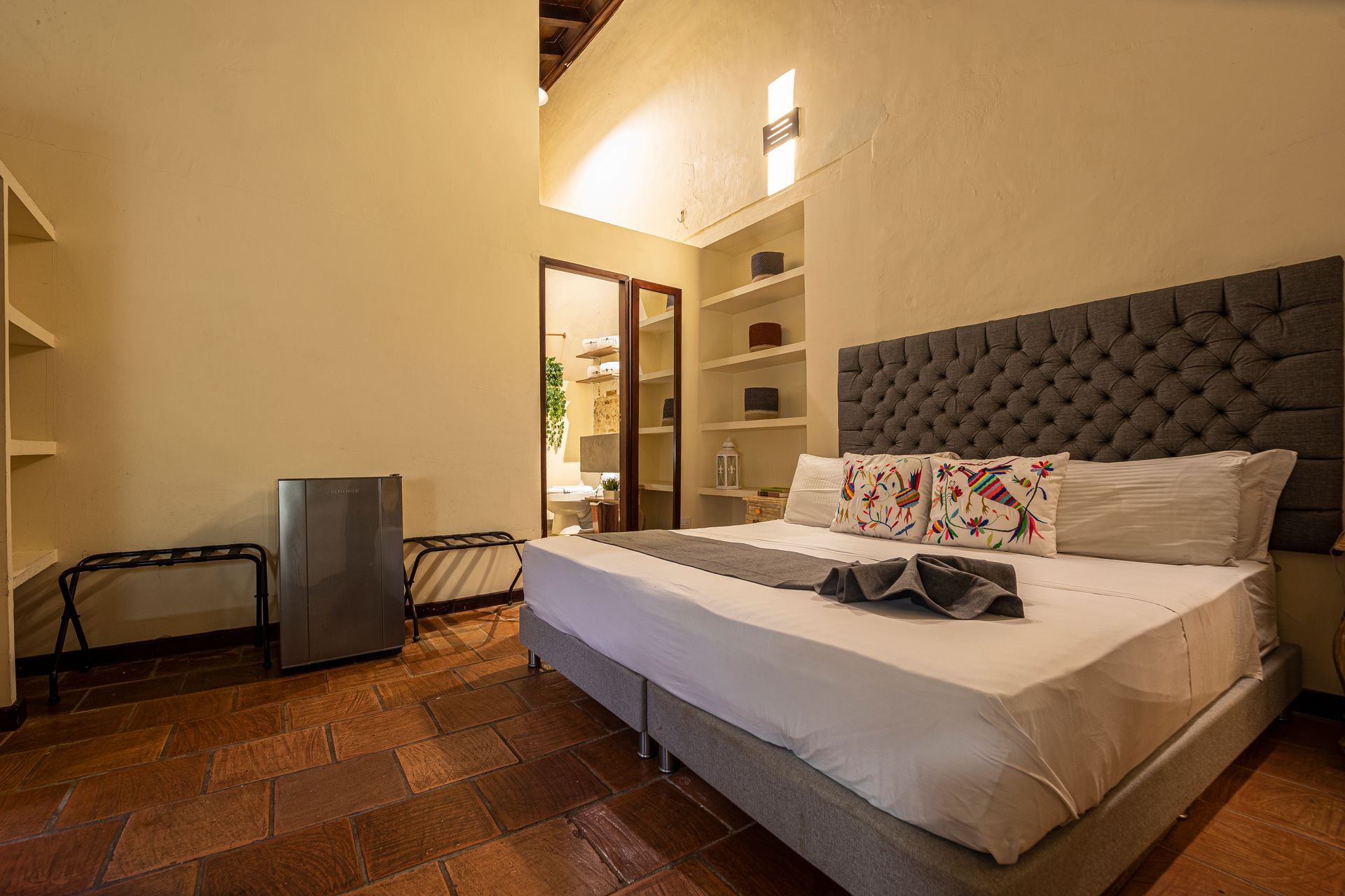 A hotel room with a king size bed and a refrigerator.