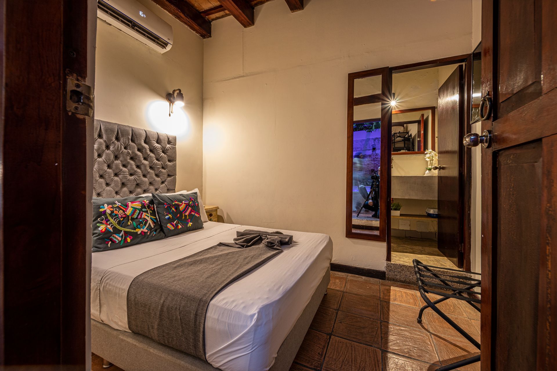 A bedroom with a bed , mirror and air conditioner.