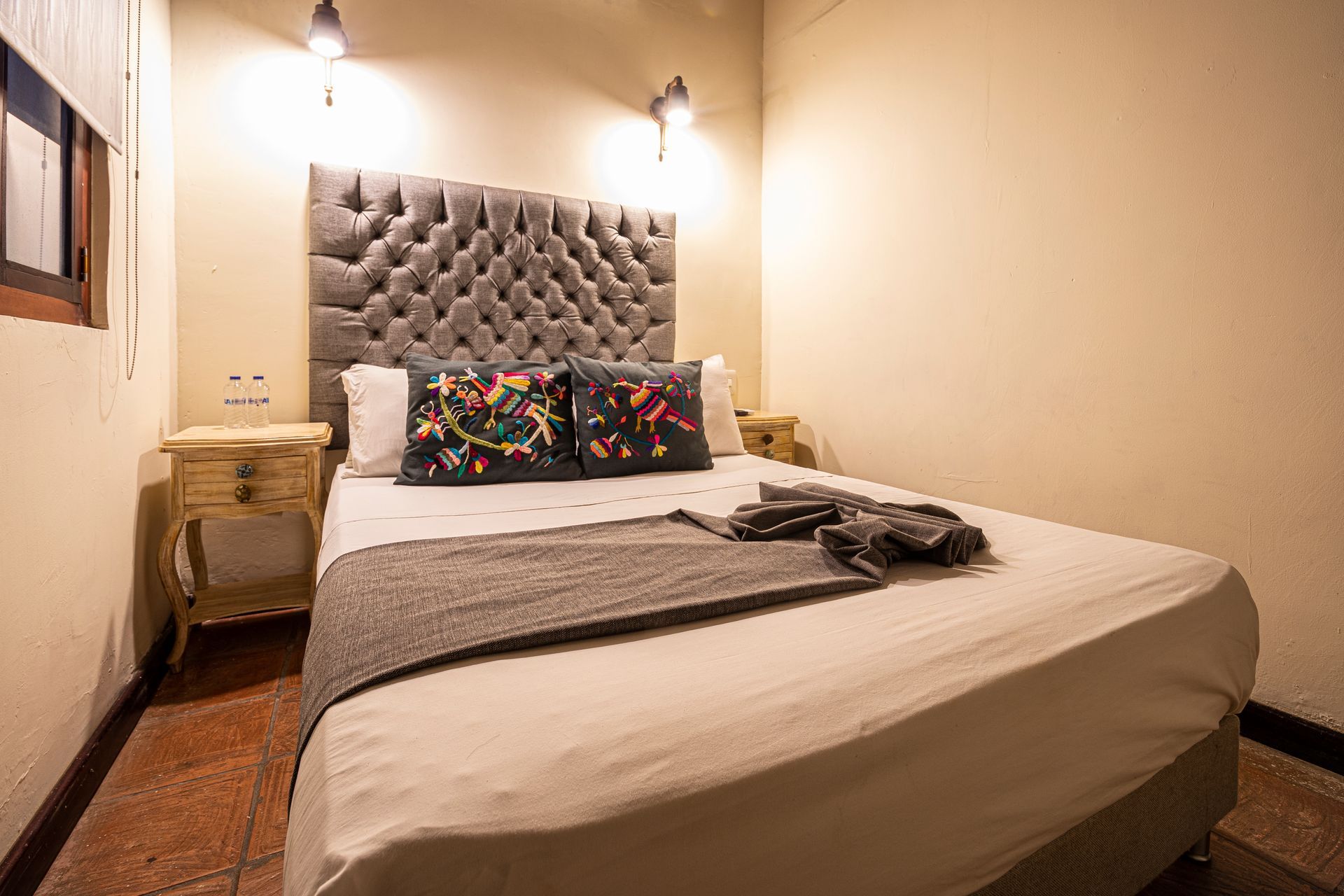 A bedroom with a bed , two nightstands and a window.