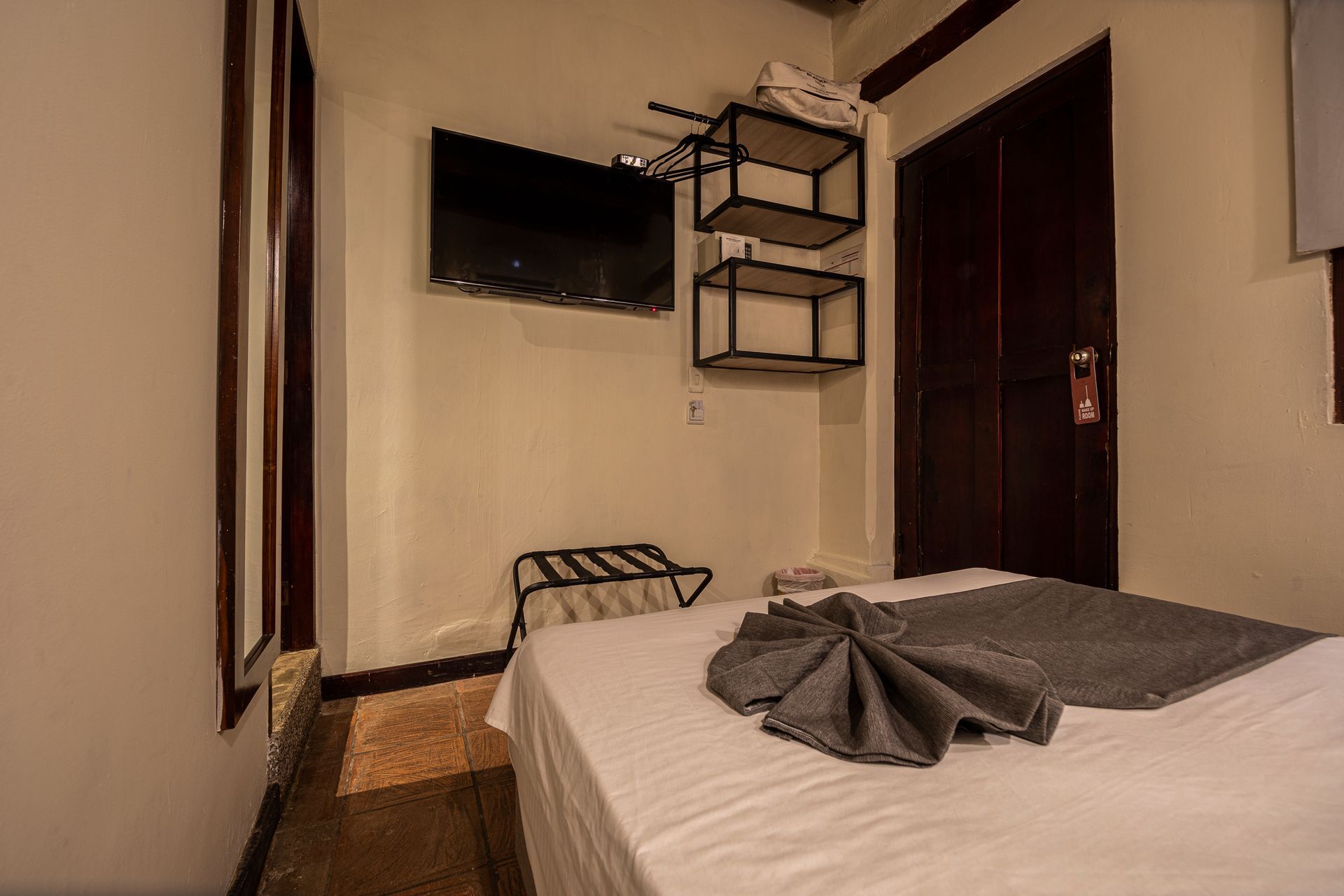 A hotel room with a bed , television , and shelves.