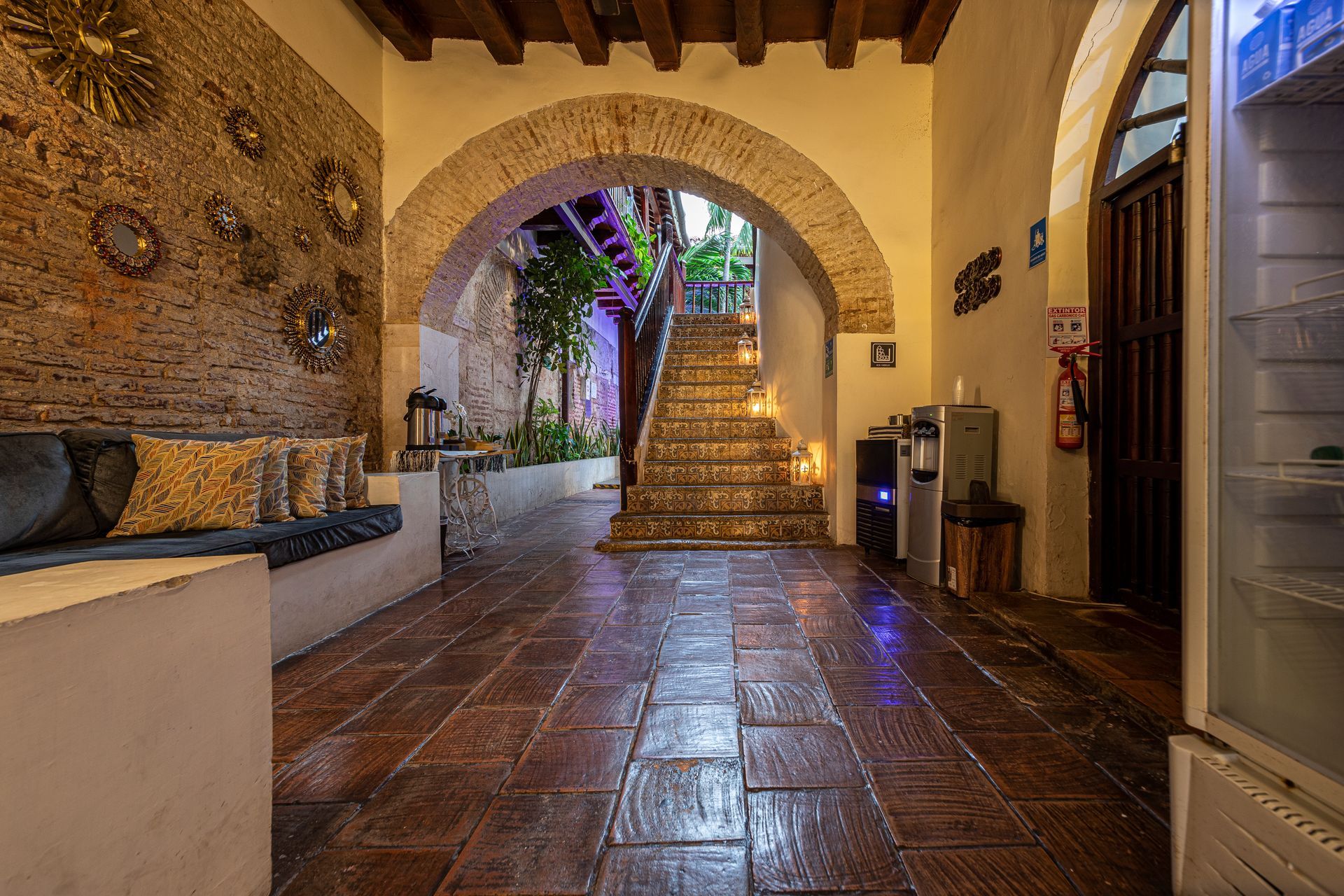 A hallway with a brick floor and stairs leading up to the second floor.
