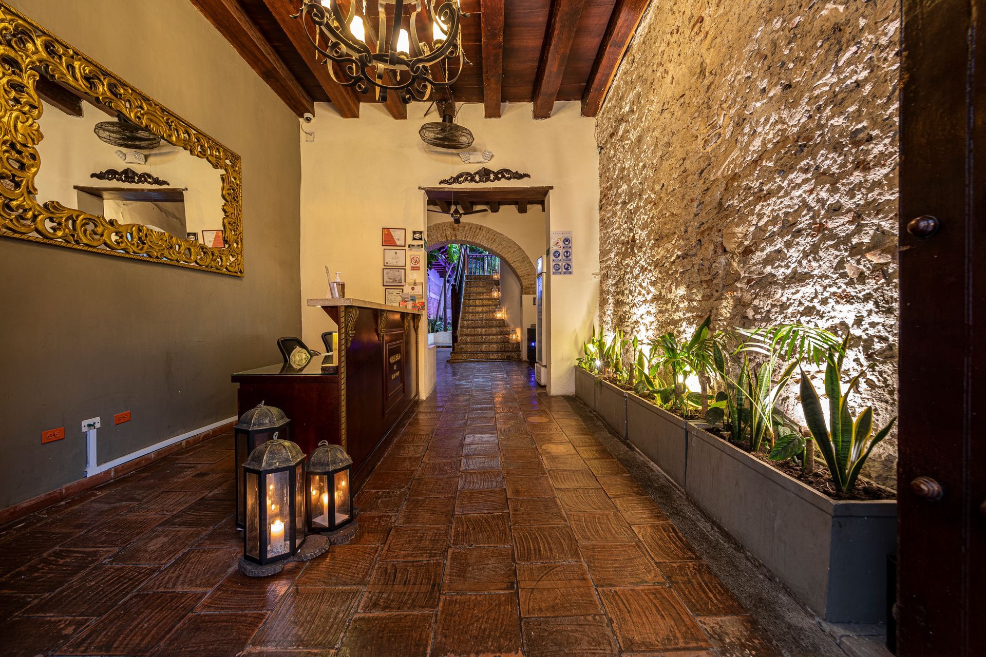 A long hallway with lanterns on the floor and a chandelier hanging from the ceiling.