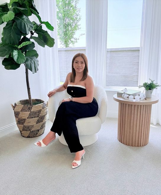 A woman is sitting at a desk with a laptop and a vase of flowers.