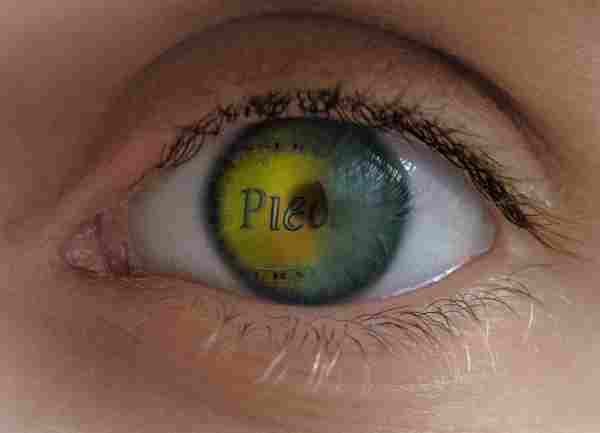 Primer plano de un ojo humano con iris amarillo y verde, en el que aparece la palabra 