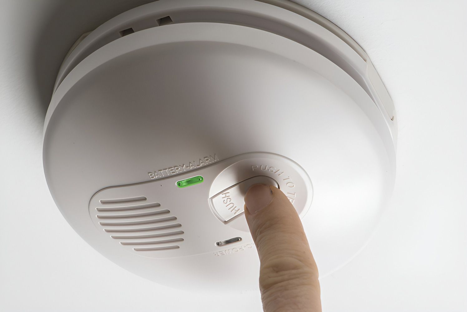 A Person is Pressing a Button on a Smoke Detector — Cairns Synergy Electrical in Manunda, QLD