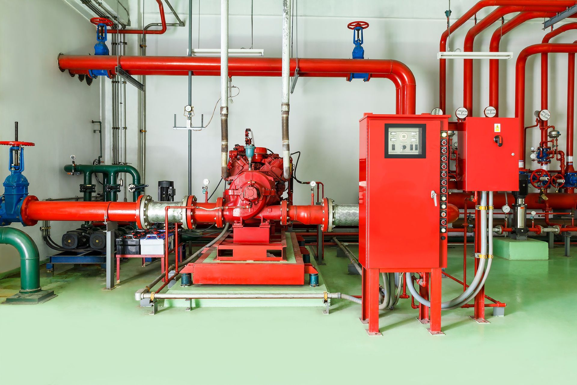 Fire pump room with red pipes, pump, and control panel.