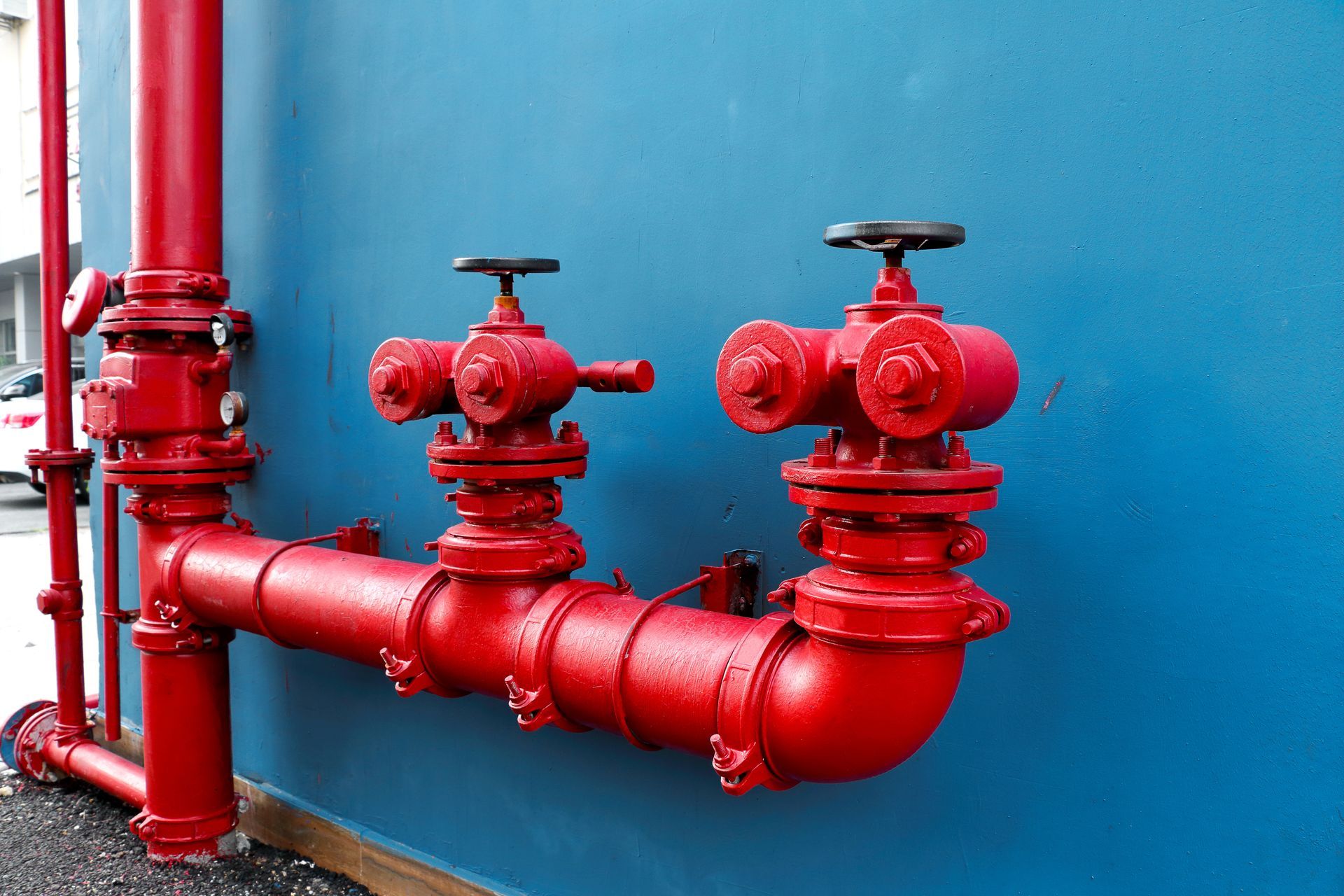 Red fire hydrant pipes against a blue wall.