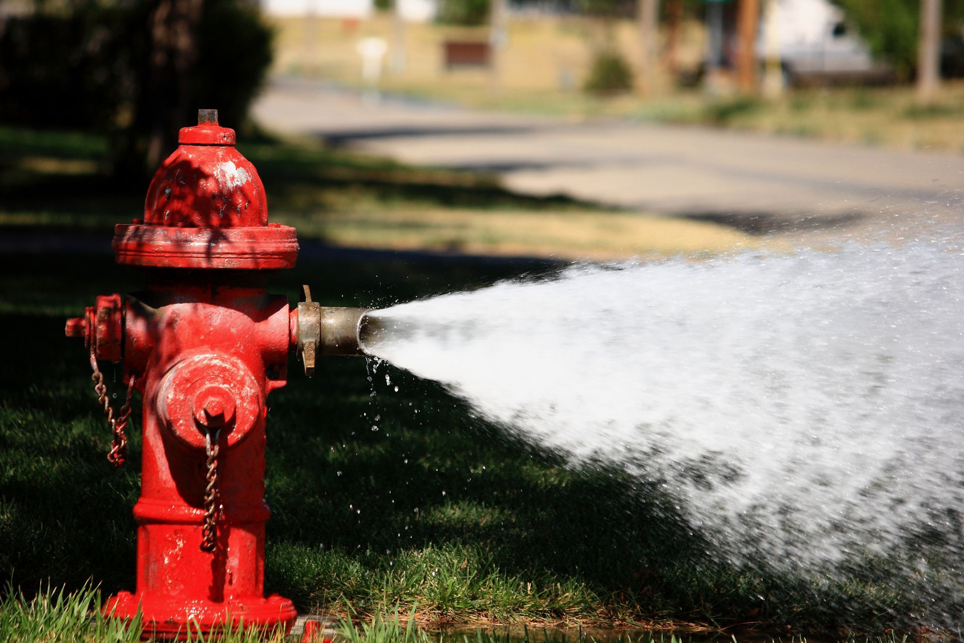 Red fire hydrant spraying water onto grass.